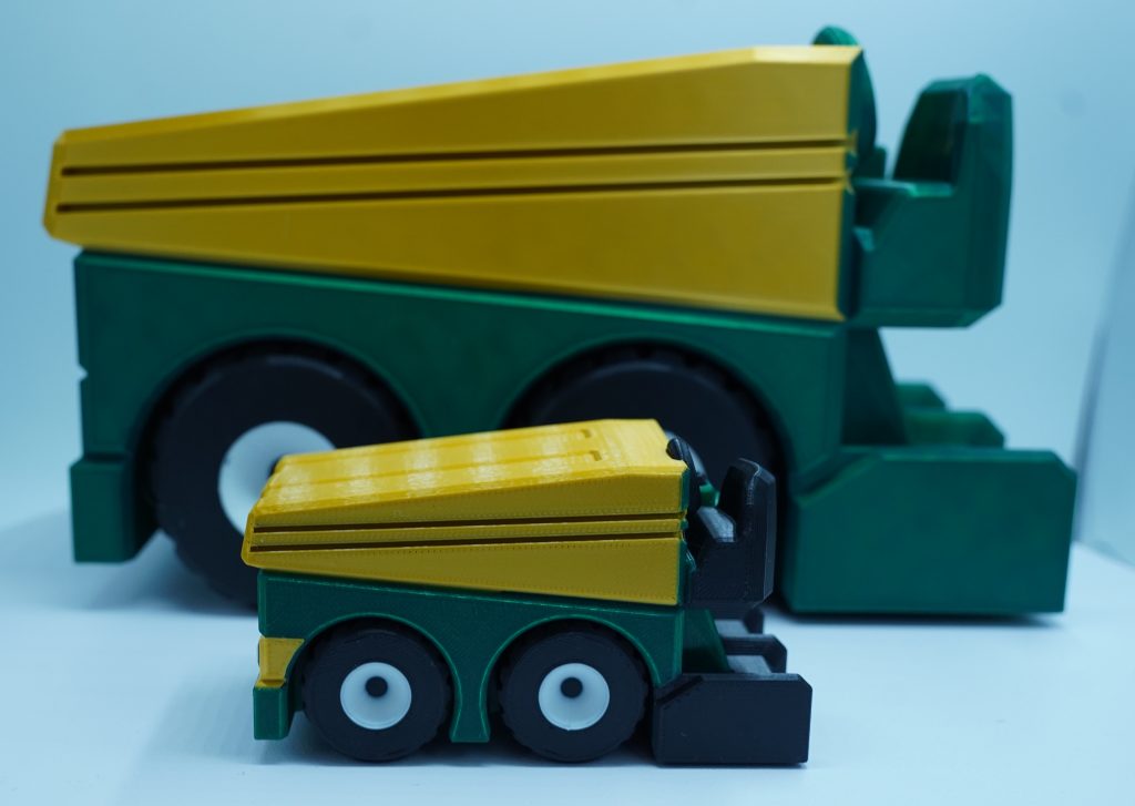 This is an image of two replica ice resurfacing machines. They are green and yellow and about three and six inches in height each.