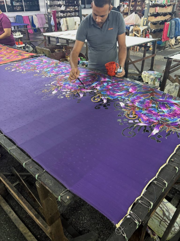 Picutre of a batik worker paitning on the product.