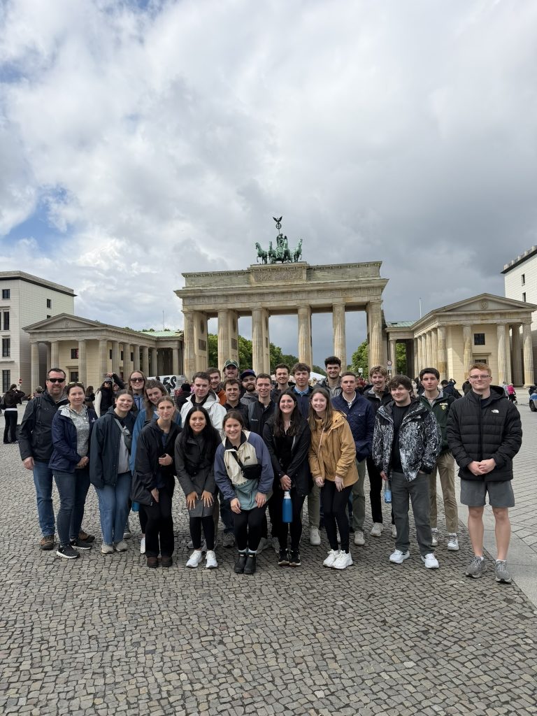 This image shows a large group of college students who are traveling abroad. They are standing together for the photo and smiling. 