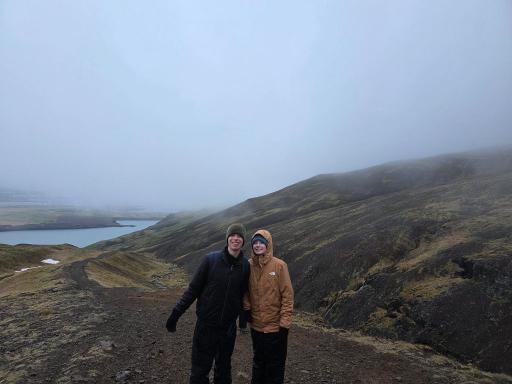 This is an image of two Clarkson students standing in front of a mountain and river. They are smiling for the photo.