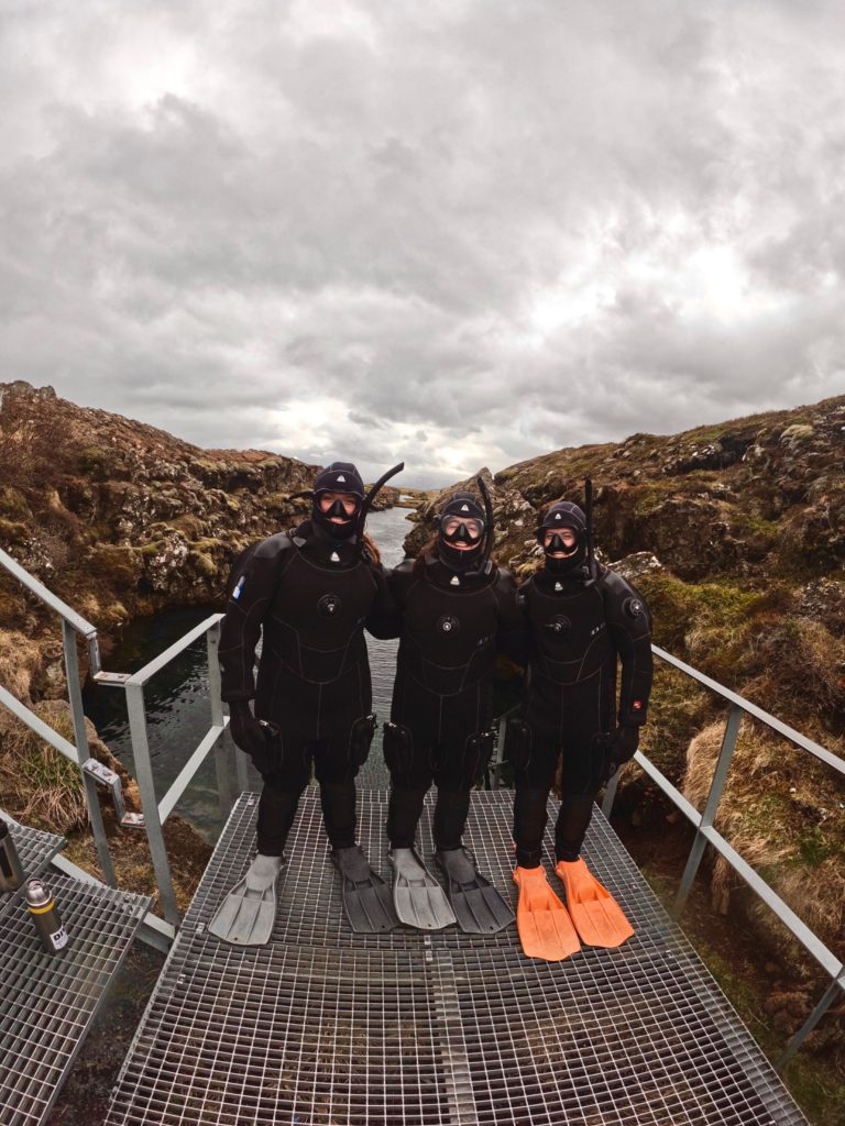 this is an image of three college students who are wearing diving equipment and standing on a bridge while traveling abroad.